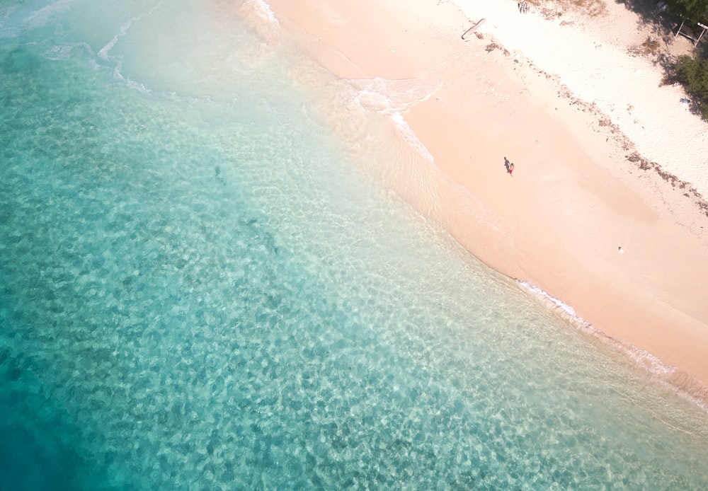 Photographie aérienne d’une personne sur une plage de sable blanc
