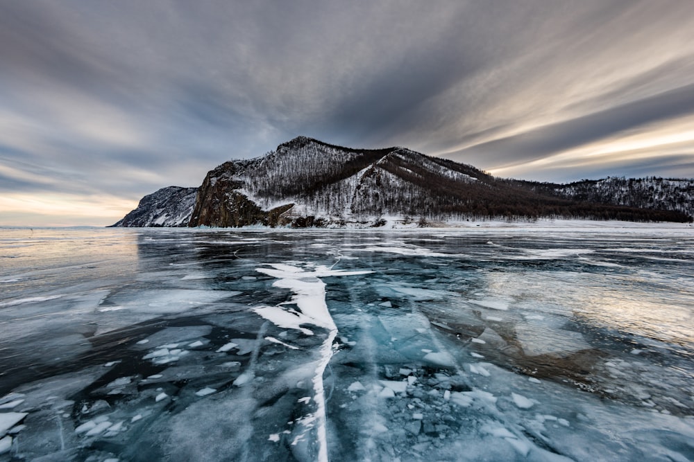 melting ice on water near gray mountain at daytime