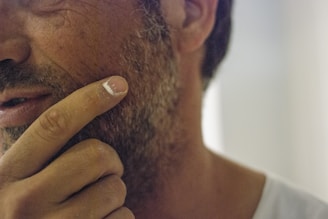 Close-up of a man gently touching his patchy beard, showing hope and confidence.