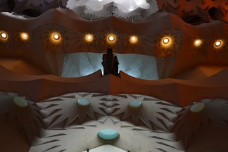 An abstract architectural design featuring pointed geometric patterns and circular light fixtures, creating a visually complex and textured surface. Soft, indirect lighting enhances the intricate details of the structure.