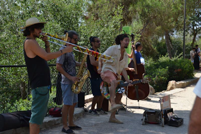 A lively group of campers playing traditional jazz instruments together outdoors under the summer sun.