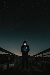 man in the middle of bridge looking to his phone