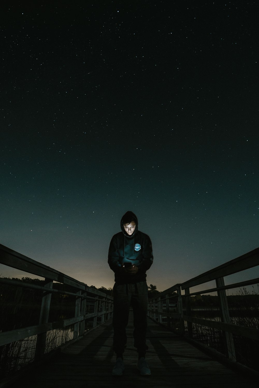 man in the middle of bridge looking to his phone