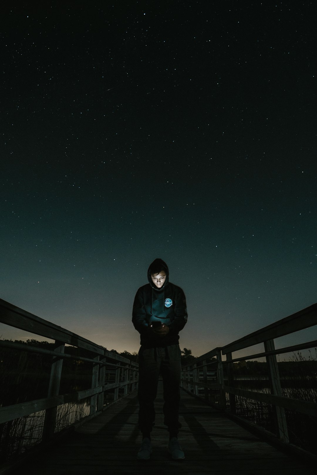 man in the middle of bridge looking to his phone