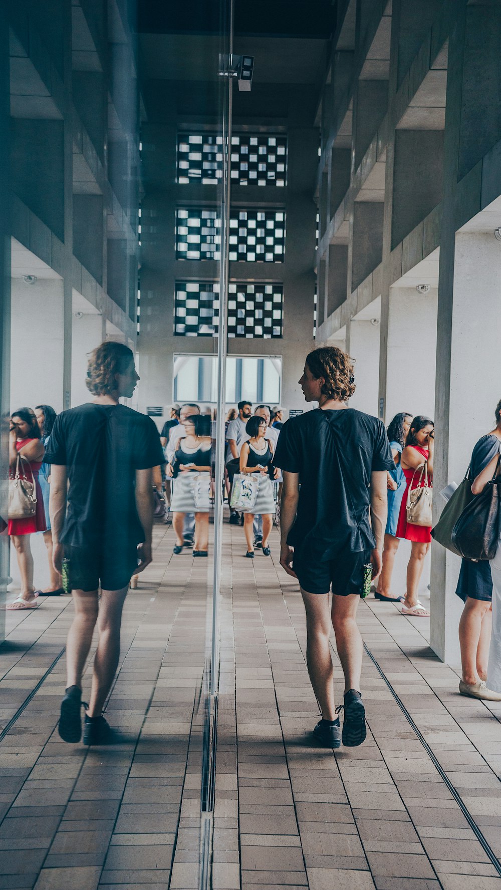 man walking beside mirror wall building