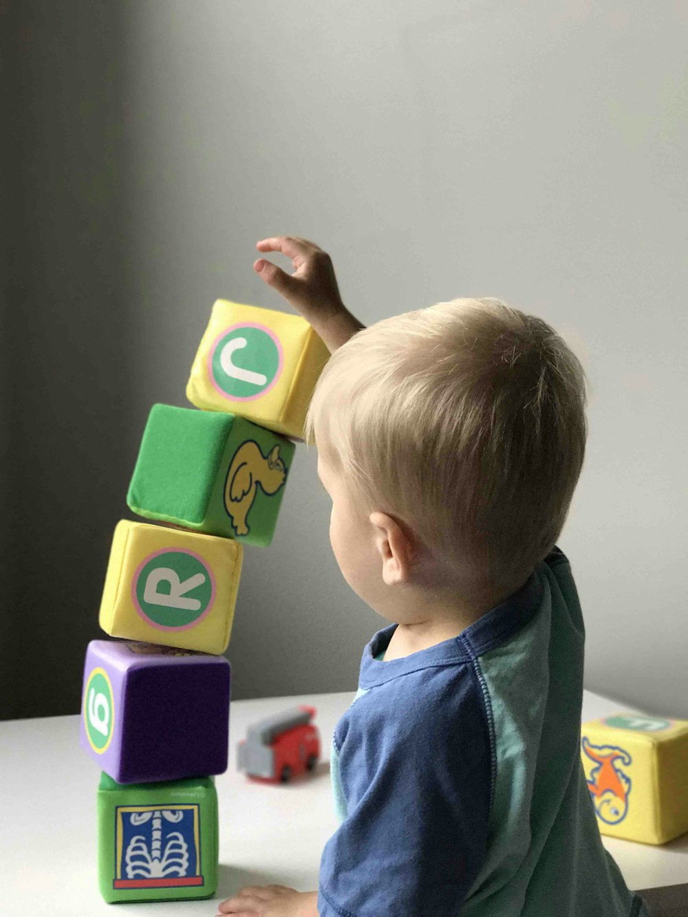 niño jugando al cubo en una mesa de madera blanca