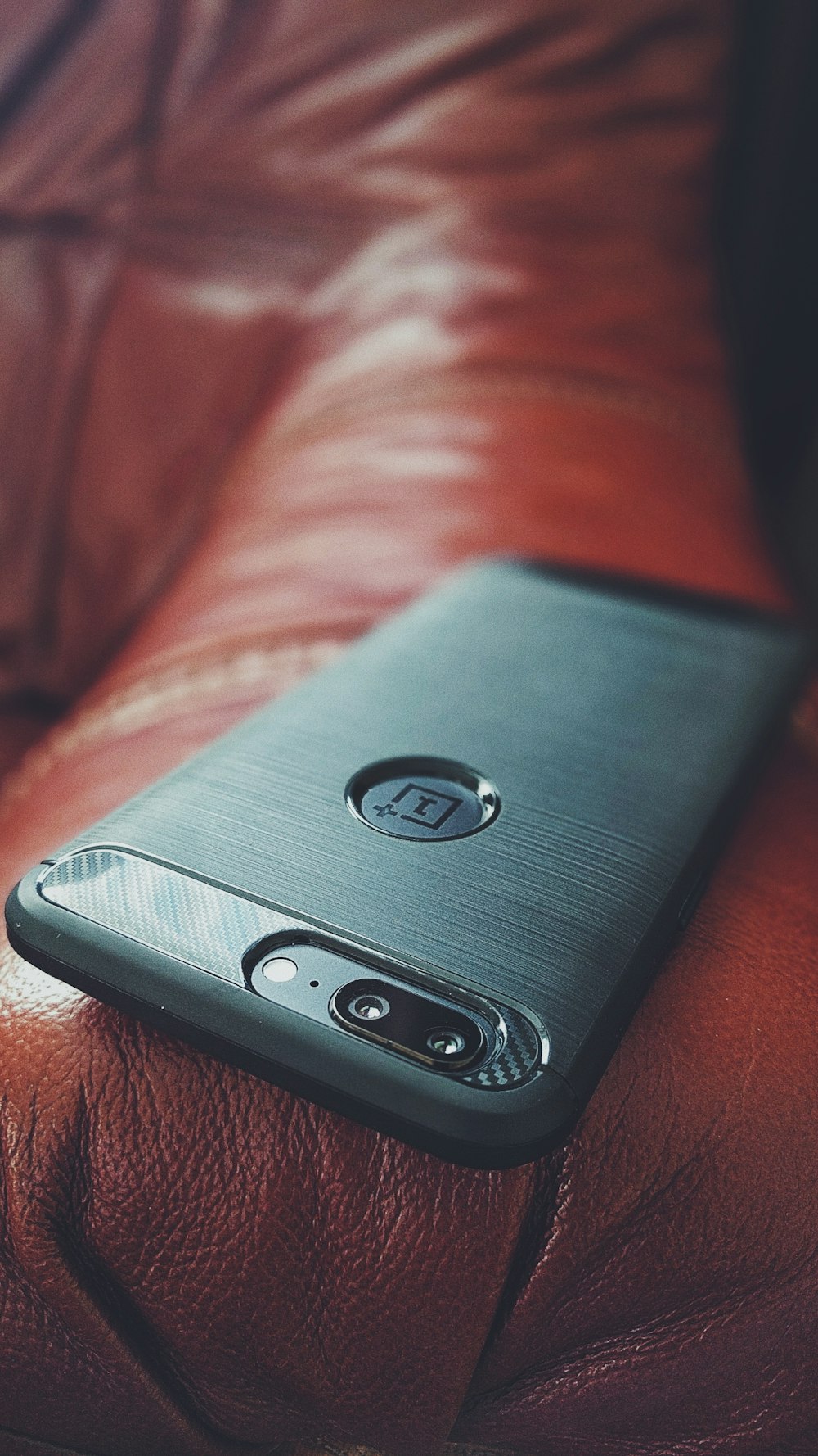 A smartphone sitting on the arm of a leather couch.