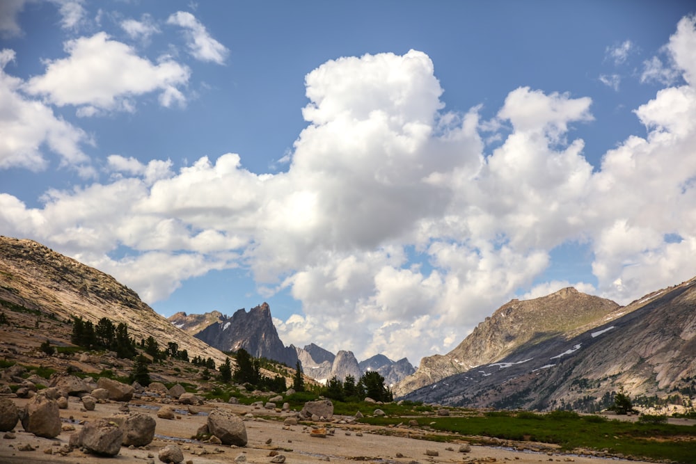 brown and green mountains under white clouds and blue sky during daytime