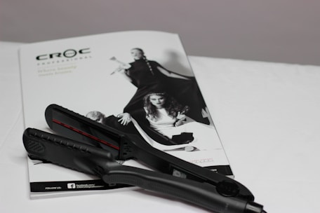 A sleek ceramic hair straightener resting on a minimalist white counter with soft natural light.