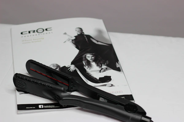 A compact, modern hair straightener glowing softly on a wooden vanity table.
