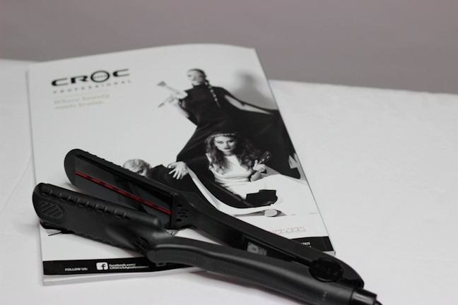 Close-up of a sleek black hair straightener resting on a marble countertop with soft morning light.
