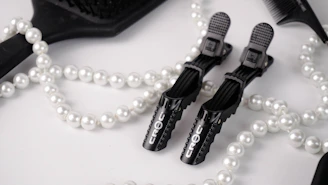 Minimalist flat lay of styling tools and accessories on a white background