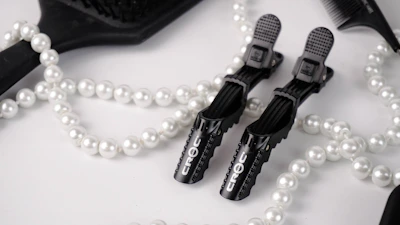 Minimalist flat lay of styling tools and accessories on a white background