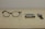 A pair of black-rimmed glasses, a smartphone, and a smartwatch are arranged side by side on a beige surface. The items suggest a modern, tech-oriented lifestyle.