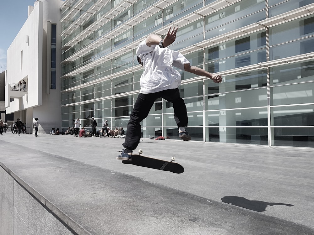 homme planche à roulettes à côté du bâtiment pendant la journée