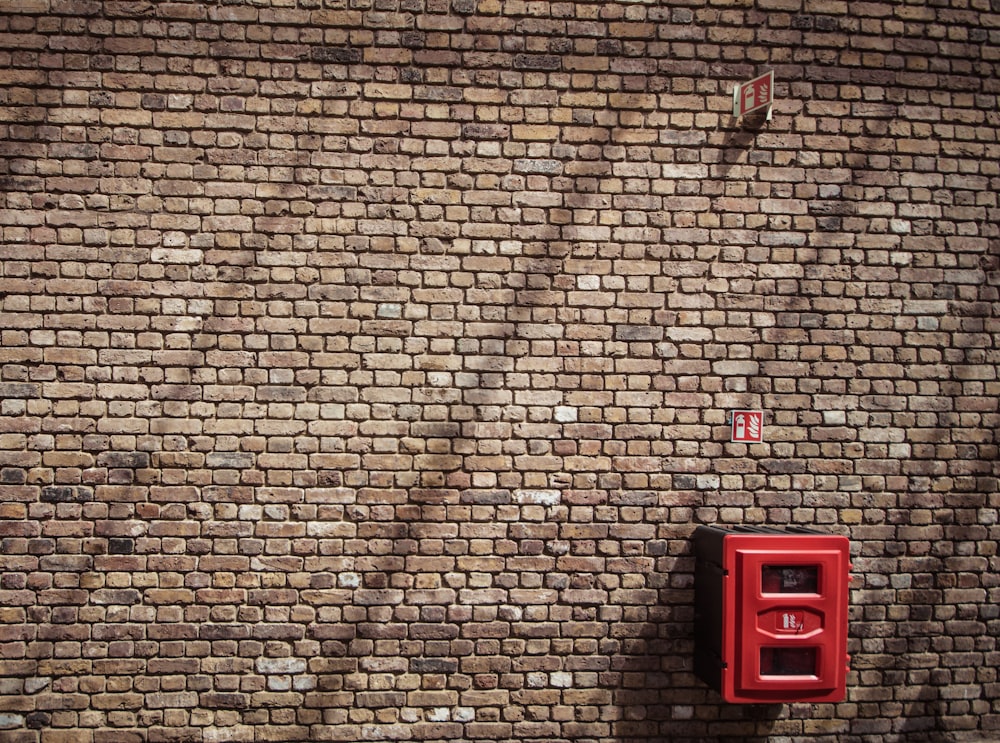 red metal case mounted on bricked wall