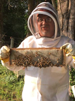 Full protective beekeeping suit hanging against a dark background, highlighting its robust fabric.