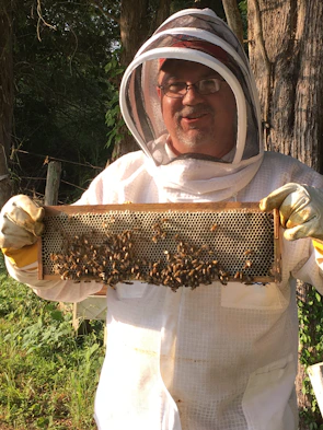 Full protective beekeeping suit hanging against a dark background, highlighting its robust fabric.