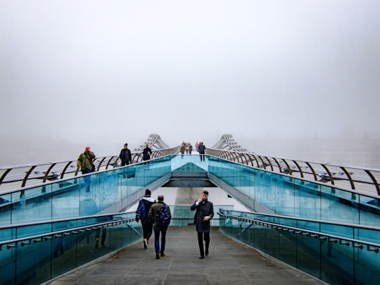 people walking near glass railings in Millennium Bridge United Kingdom