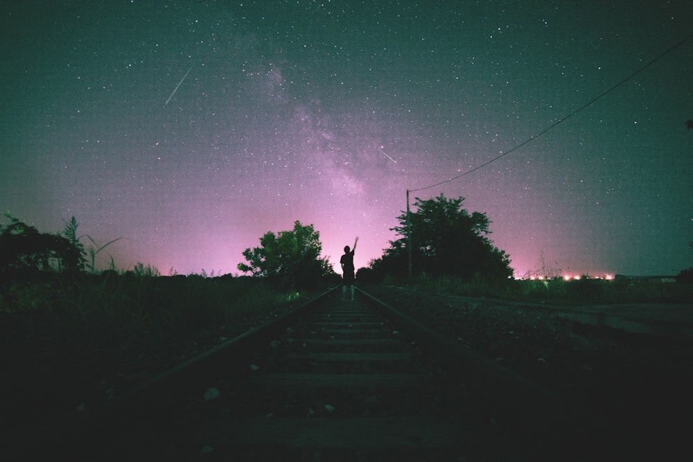 person in middle on train track during night time