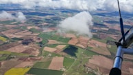Aerial view of a training plane soaring over a patchwork of green fields and winding rivers.