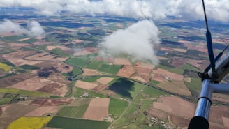 Aerial view of a training plane soaring over a patchwork of green fields and winding rivers.