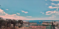 A wide shot of the seaside pickleball courts with waves gently rolling in beyond the fence.