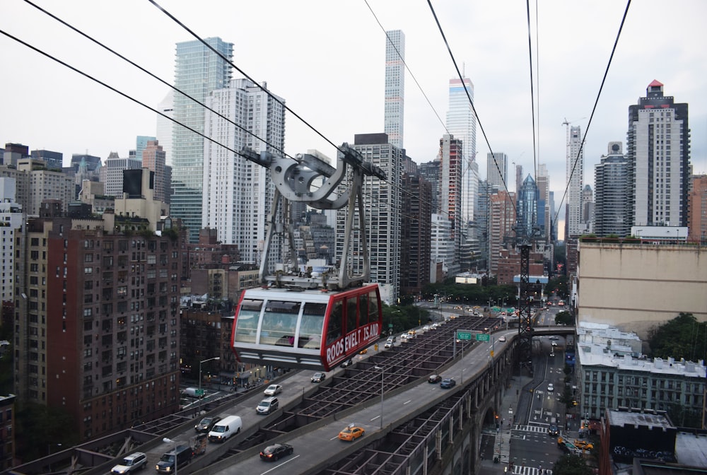 red and white cable car above grey roads at daytime