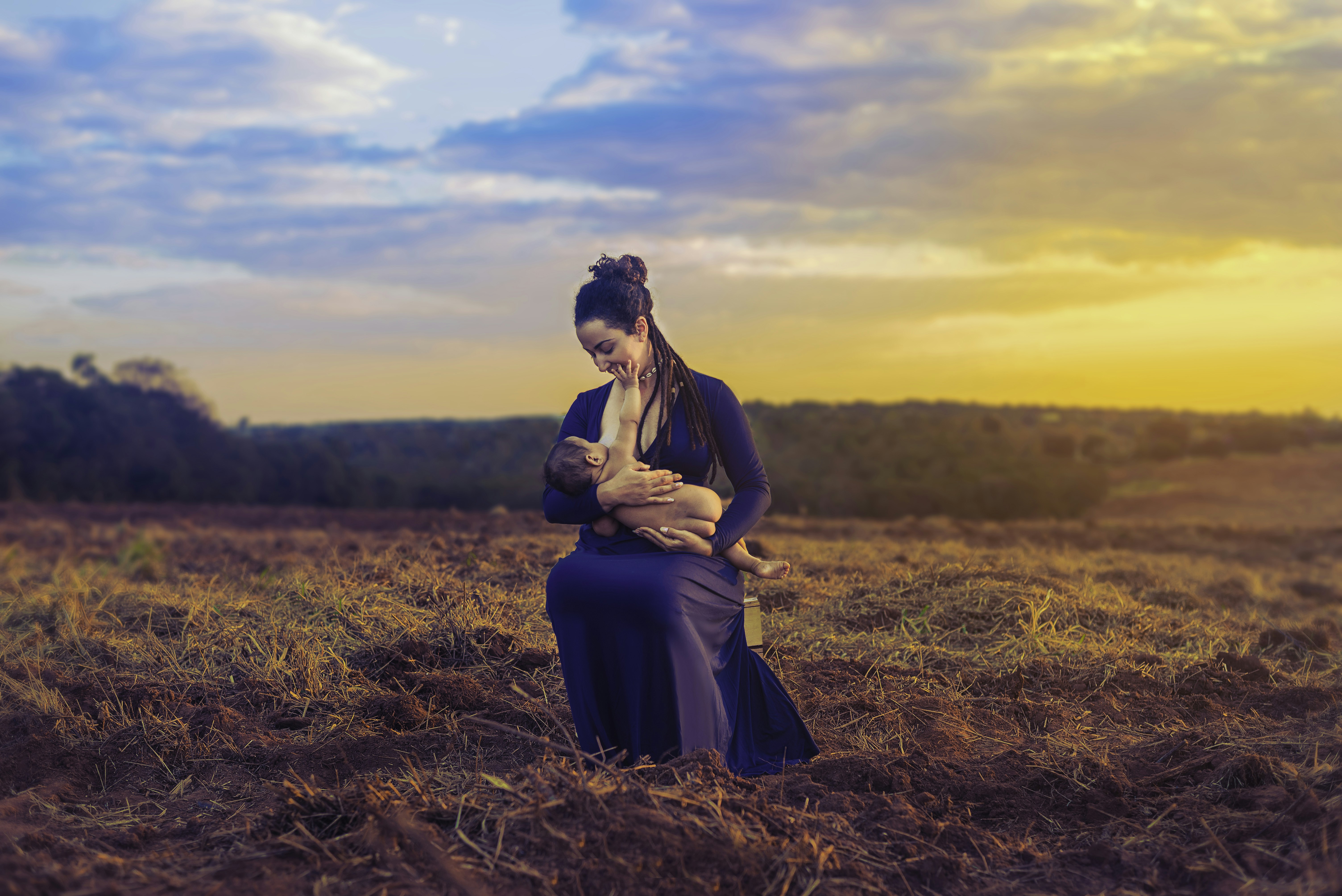 woman wearing purple long-sleeved dress while carrying baby