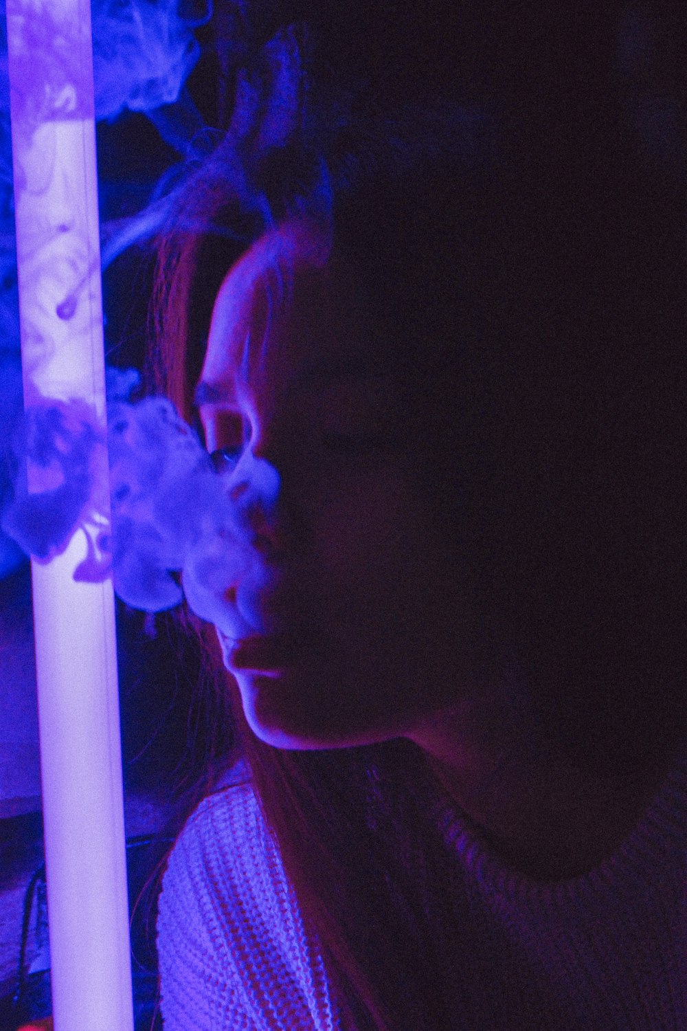 woman in white crew-neck top near light while smoking