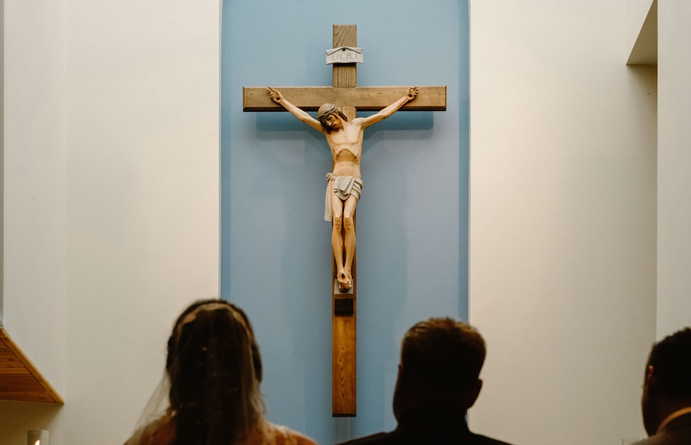three people staring at the crucifix