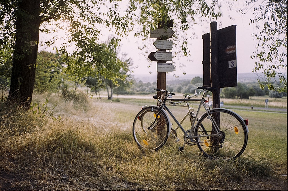 white commuter bike beside white signage near trees at daytime