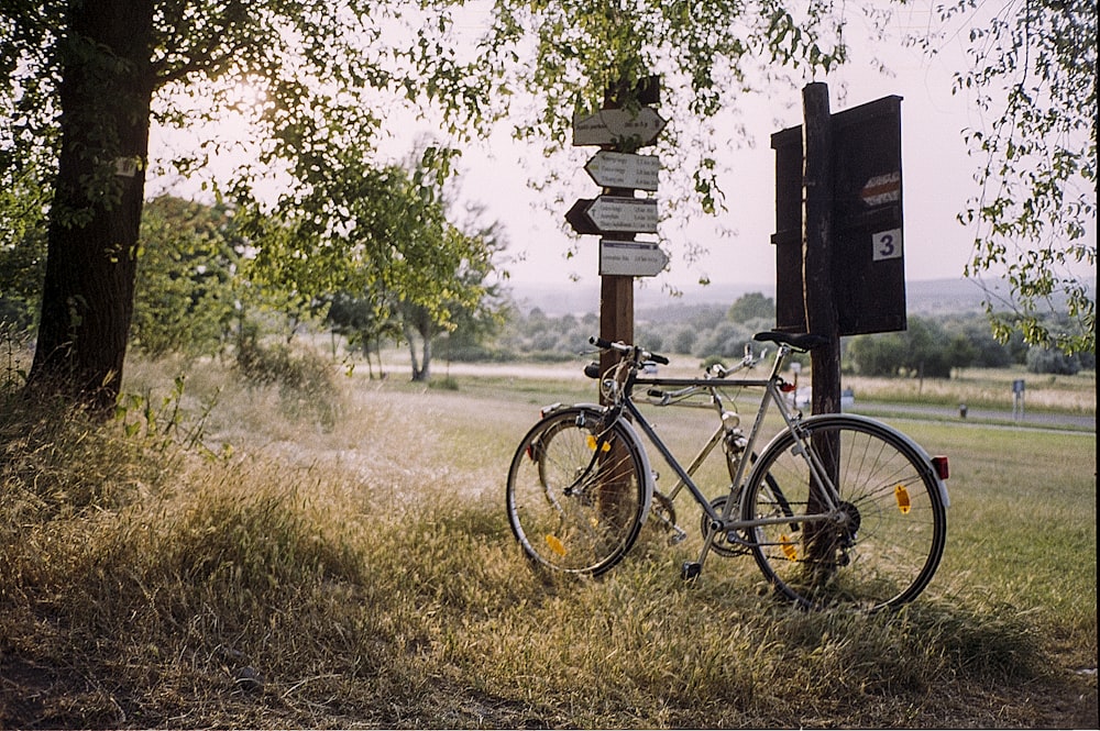 昼間、木々の近くの白い看板の横の白い通勤用自転車