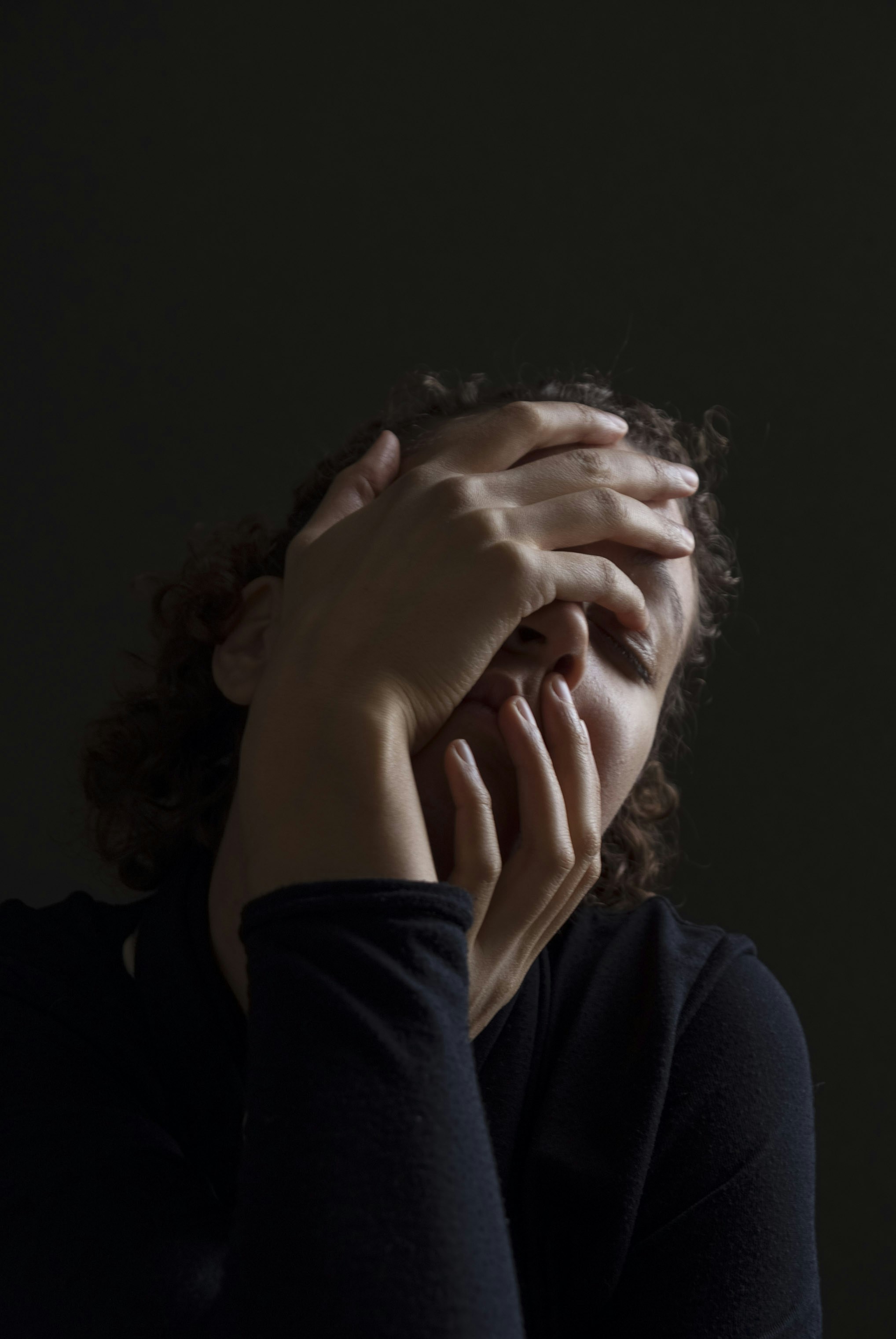 woman wearing blue long-sleeved shirt touching her face