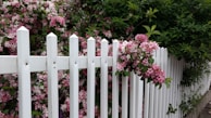 A charming white picket fence framing a colorful garden in full bloom.