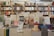 A bookstore with shelves filled with a variety of books arranged neatly. There is a table in the foreground stacked with several different books with colorful covers, featuring notable authors and titles. Books are stacked both vertically and horizontally, showcasing different genres.