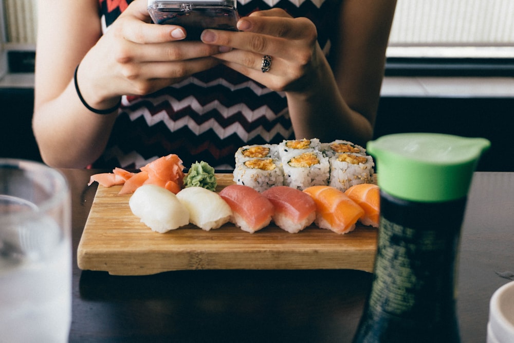 Person, die vor einem Sushi-Gericht auf dem Tisch sitzt