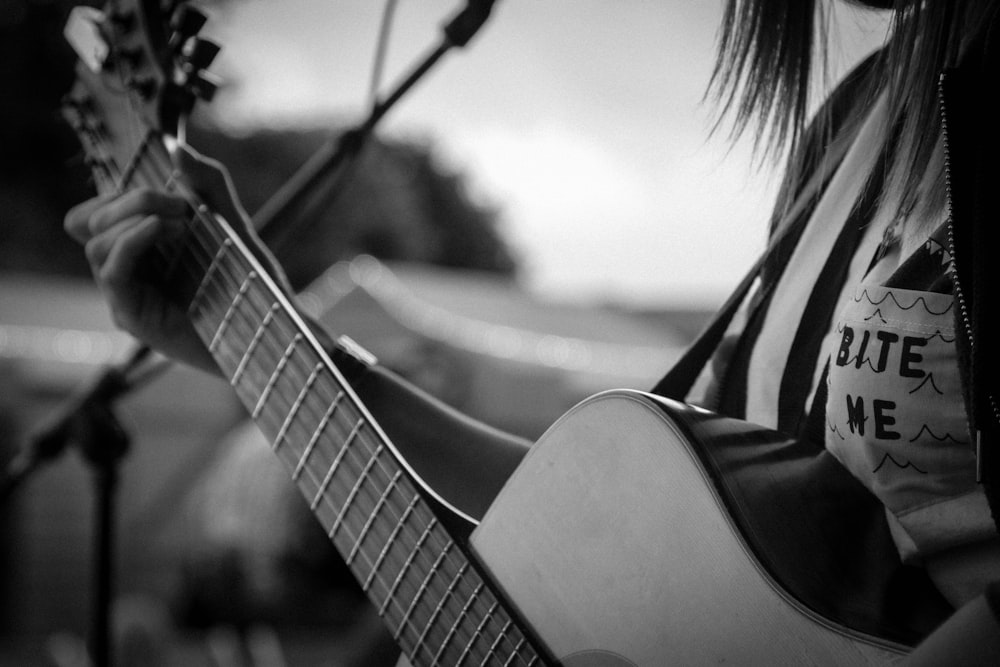 grayscale and selective focus photography of woman playing guitar