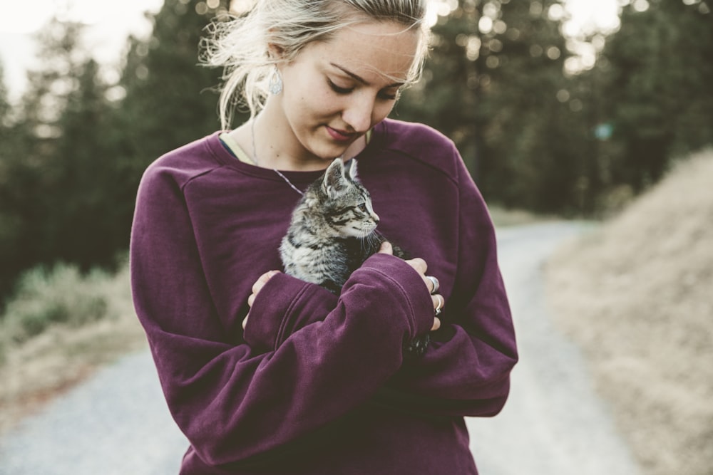 Fotografia de foco seletivo da mulher abraçando gatinho cinza
