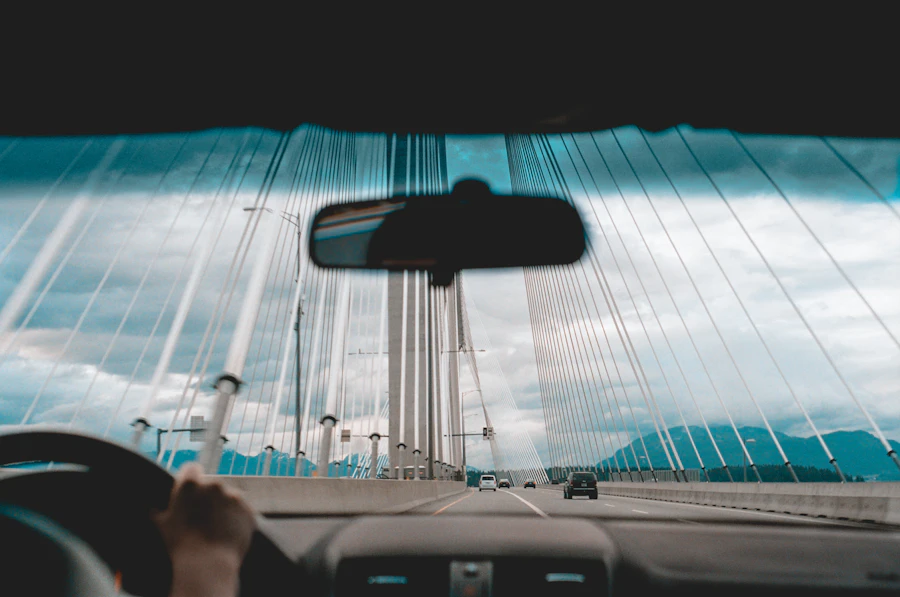 Driver's hands on the steering wheel while crossing a cable-stayed bridge under heavy clouds