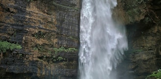 person standing on brown rock formation looking at waterfalls during daytime