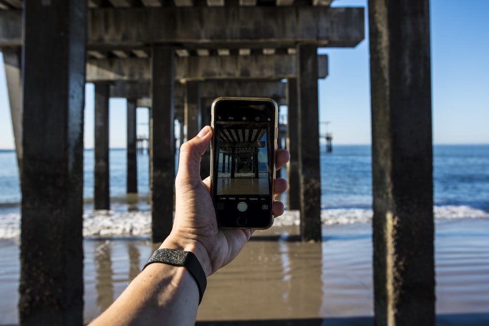 person holding black smartphone taking photo of sea during daytime
