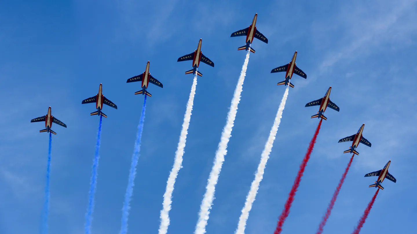 Jets flying in formation trailing coloured smoke