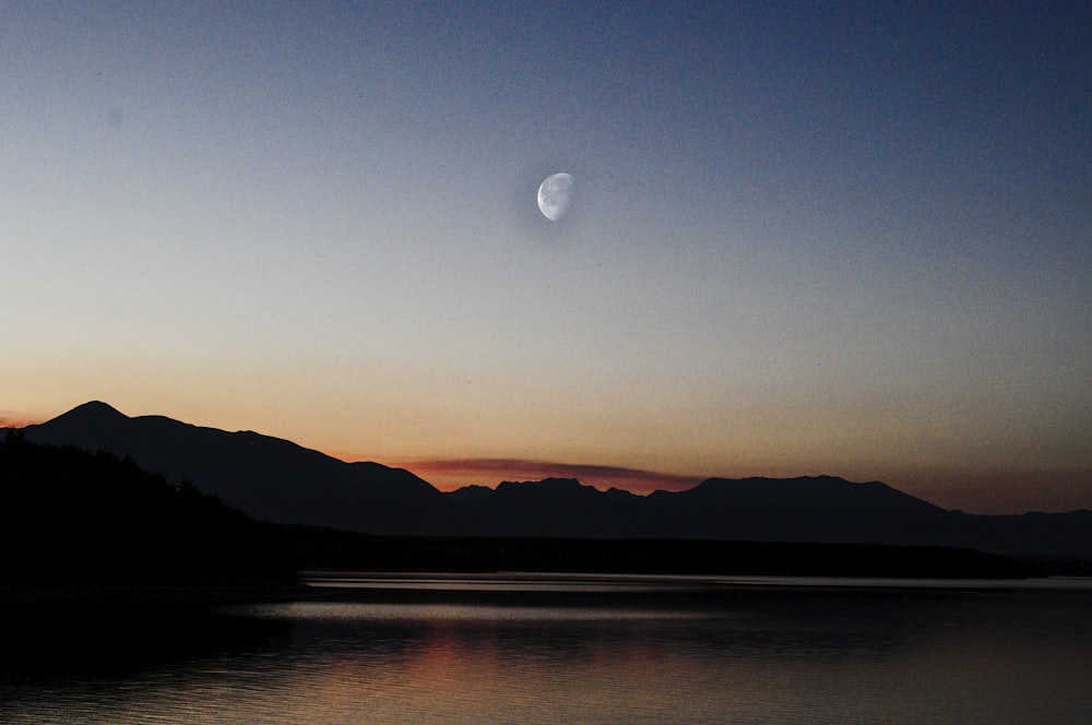 silhouette of mountains near body of water during golden hour