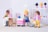A scene with colorful plastic figures resembling people in a playful and imaginative setting. The figures appear to be set in a salon environment with a chair, a white and pink counter, and what looks like a display shelf in the background.