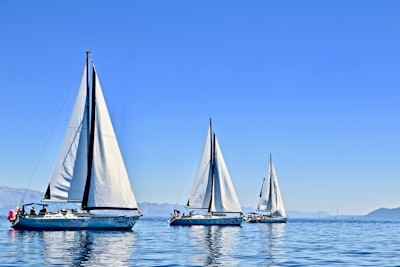 three sail boats on water during daytime