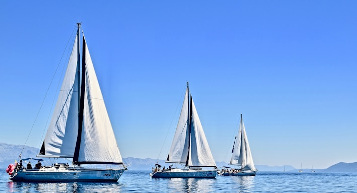 three sail boats on water during daytime