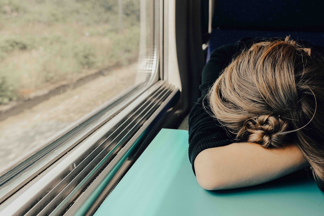 Mujer a bordo de tren durmiendo apoyada sobre escritorio