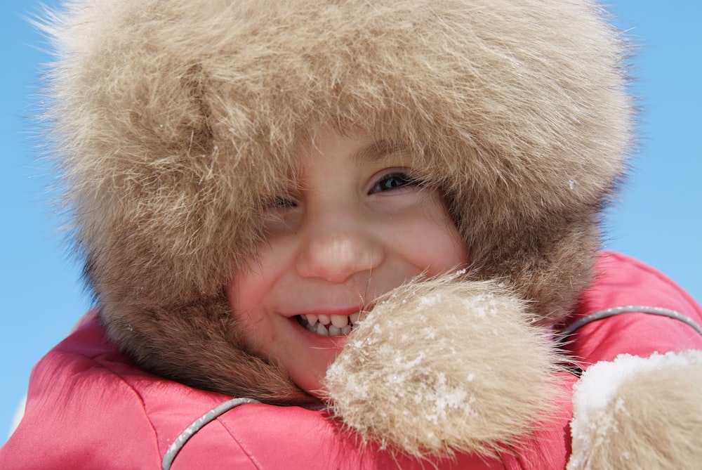 fille en manteau de fourrure rose et marron souriant