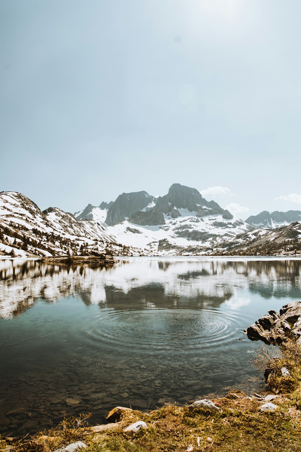 body of water surrounded by mountains covered with snow during daytime